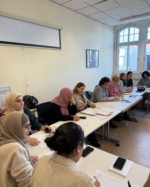 Frauen sitzen als Arbeitsgruppe um einen L-förmigen Tisch