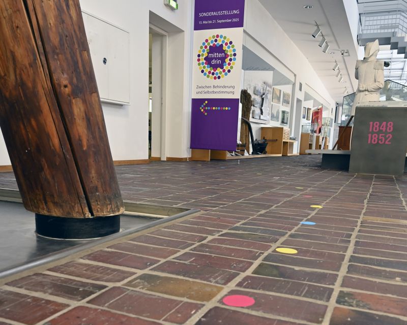 Blich in vom Boden mit Aufklebern zum Saaleingang mit Ausstellungsbanner