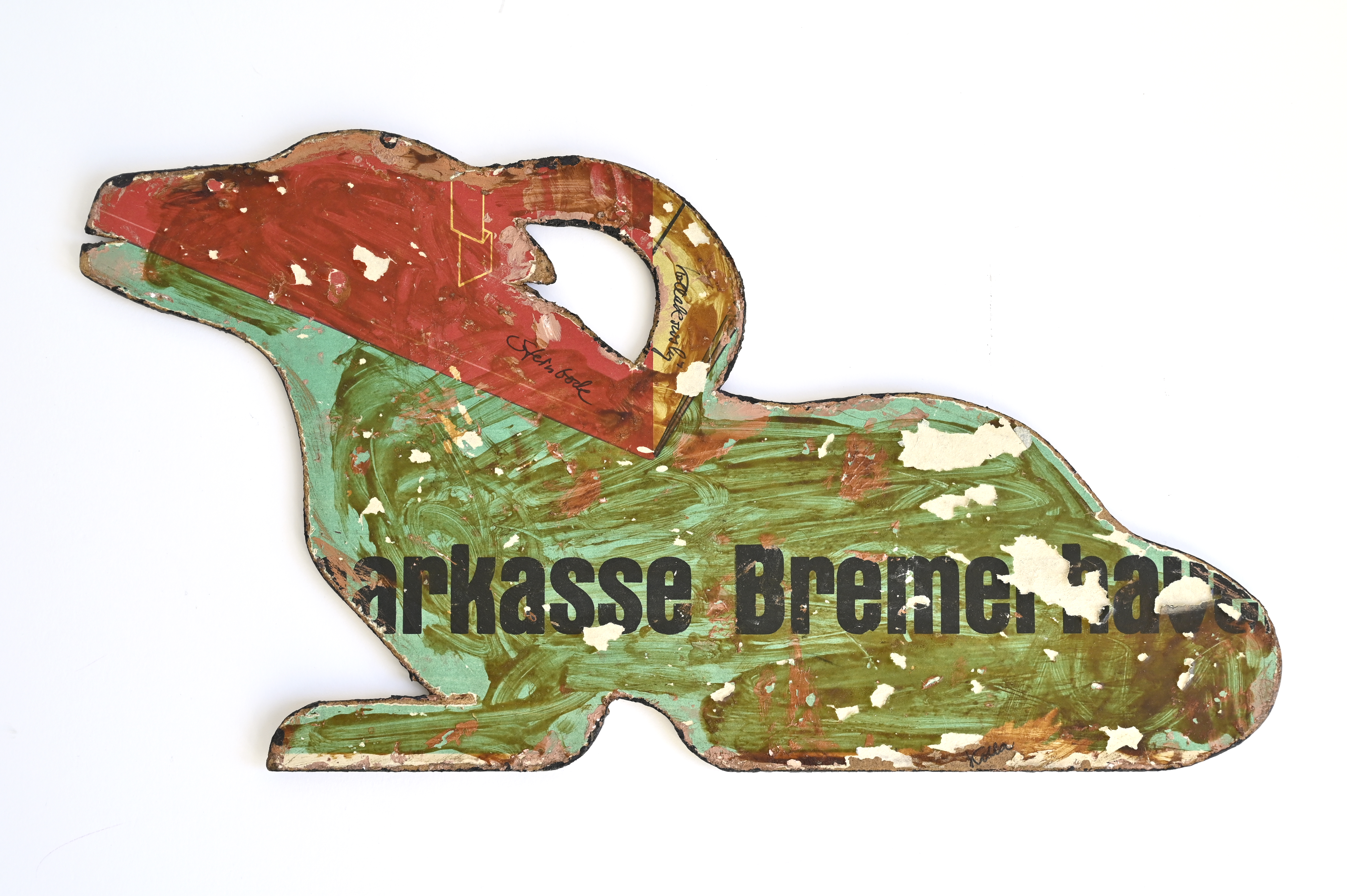 Steinbockfigur aus dünner Holzplatte gesägt. Bemalt in Grüntönen. Fragmente des Schriftzuges "Sparkasse Bremerhaven".